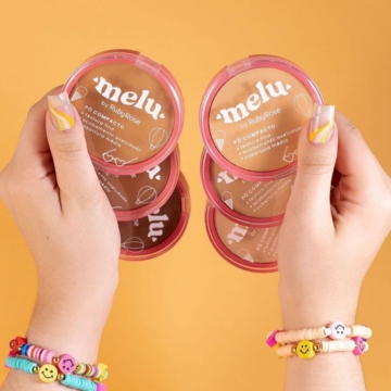 a imagem mostra duas mãos, cada uma segurando três variações de pó compacto da marca melu
